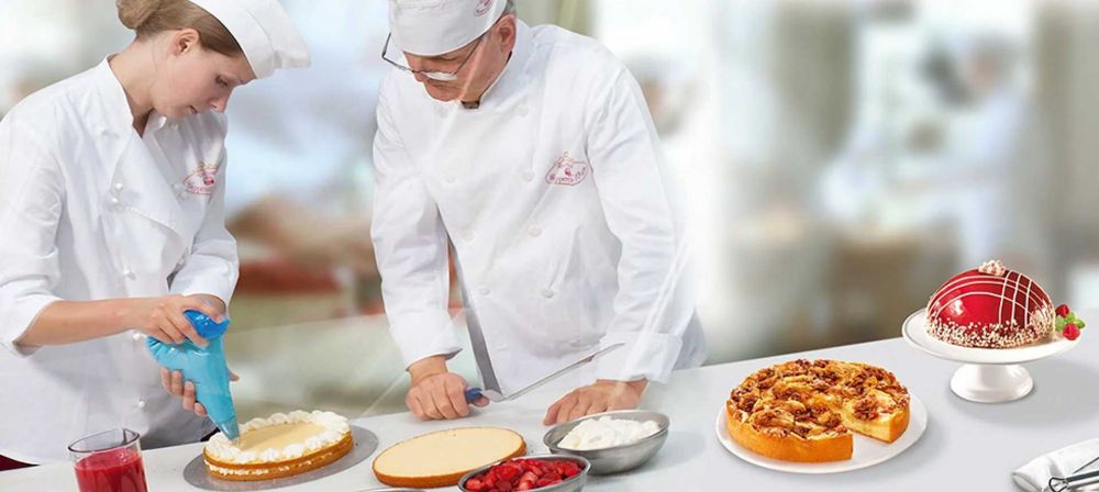 Zwei Konditoren bereiten in einer Backstube Torten zu und dekorieren Gebäck als Symbol für handwerkliche Produktion, Präzision und Lebensmittelverarbeitung