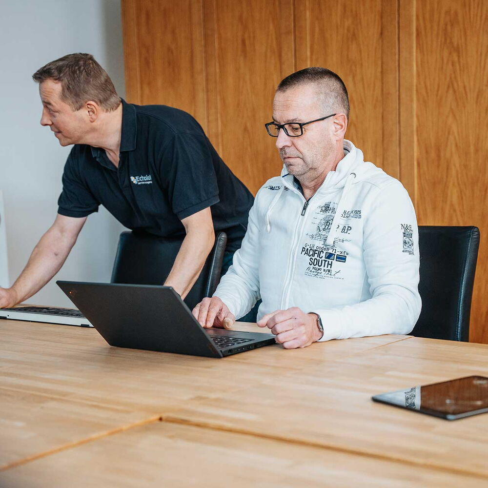 Zwei Mitarbeitende von mIT solutions arbeiten gemeinsam am Laptop im Büro und stimmen sich zu digitalen Anwendungen und Prozessen ab