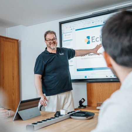 Mitarbeiter von mIT solutions präsentiert die EcholoN Software vor einem Bildschirm im Meeting und erklärt Funktionen sowie digitale Prozesse