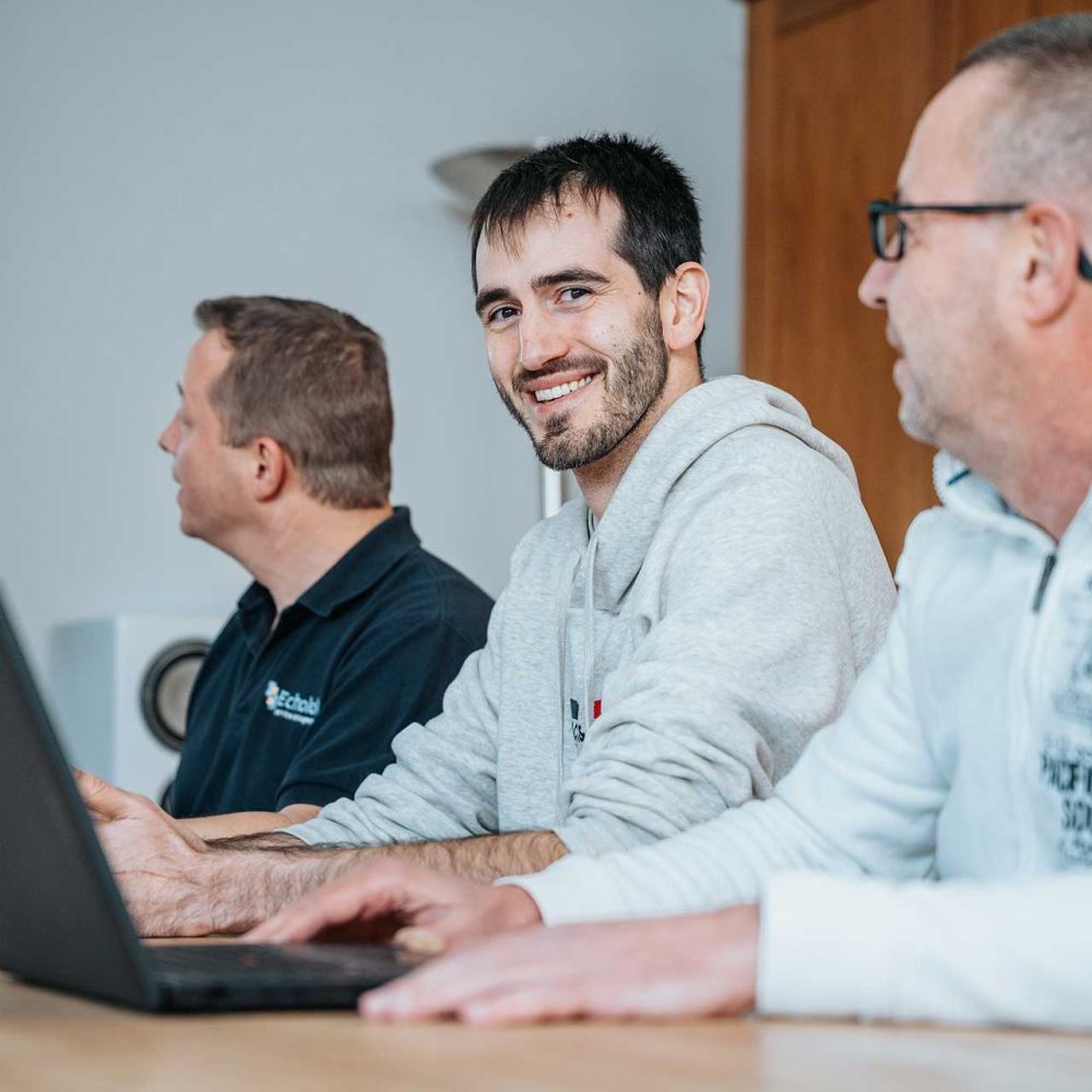 Mitarbeitende von mIT solutions arbeiten gemeinsam mit Laptop und Tablet im Meeting und stimmen sich zu digitalen Prozessen und Softwarelösungen ab