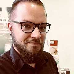 Porträt eines Mannes mit Brille und Bart, der in die Kamera blickt und einen professionellen Eindruck vermittelt