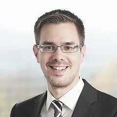 Porträt eines Mannes mit Brille im Anzug, der freundlich in die Kamera lächelt und einen professionellen Eindruck vermittelt
